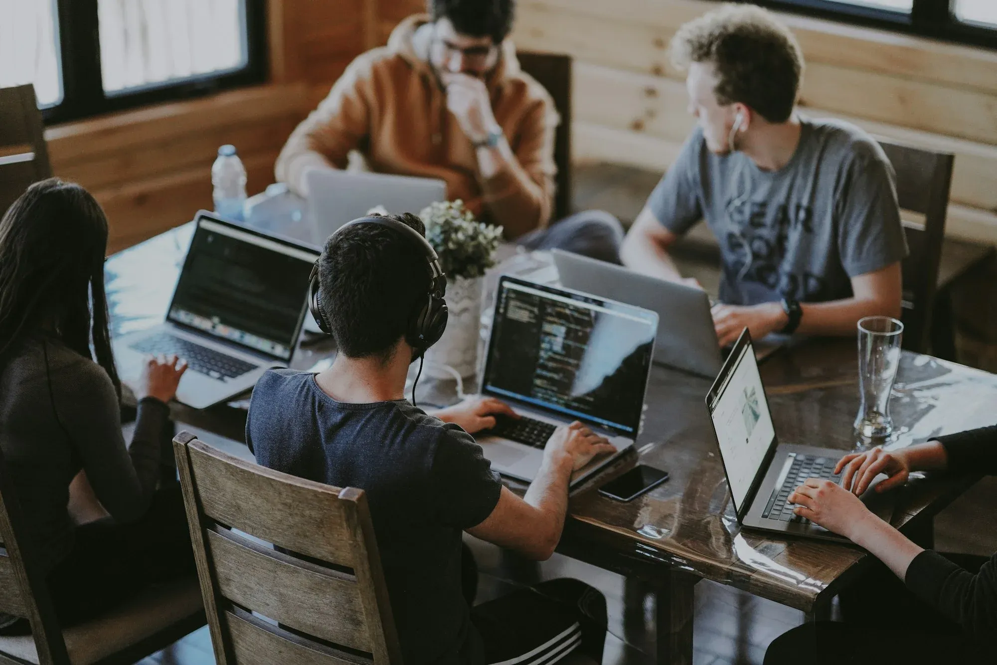 Four developers working together at one table, laptops open with code on the screens